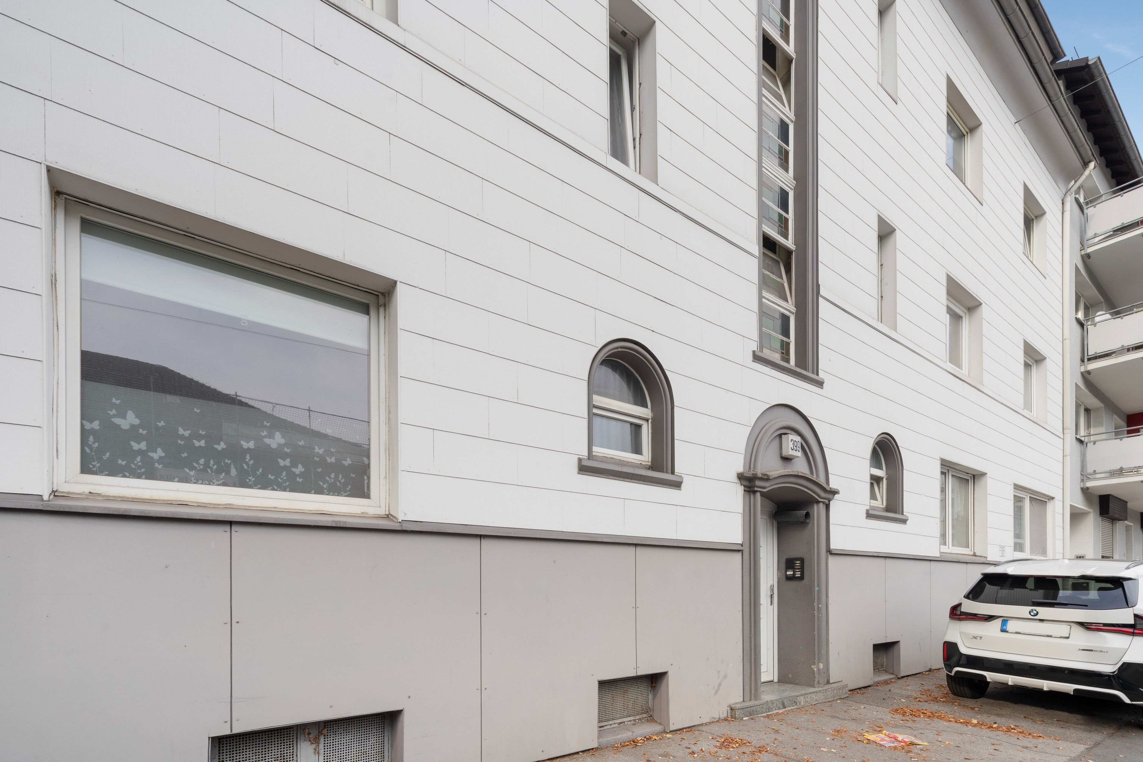 Edifici blanc amb una porta de garatge, un cotxe a la façana i el número '399' a la porta.