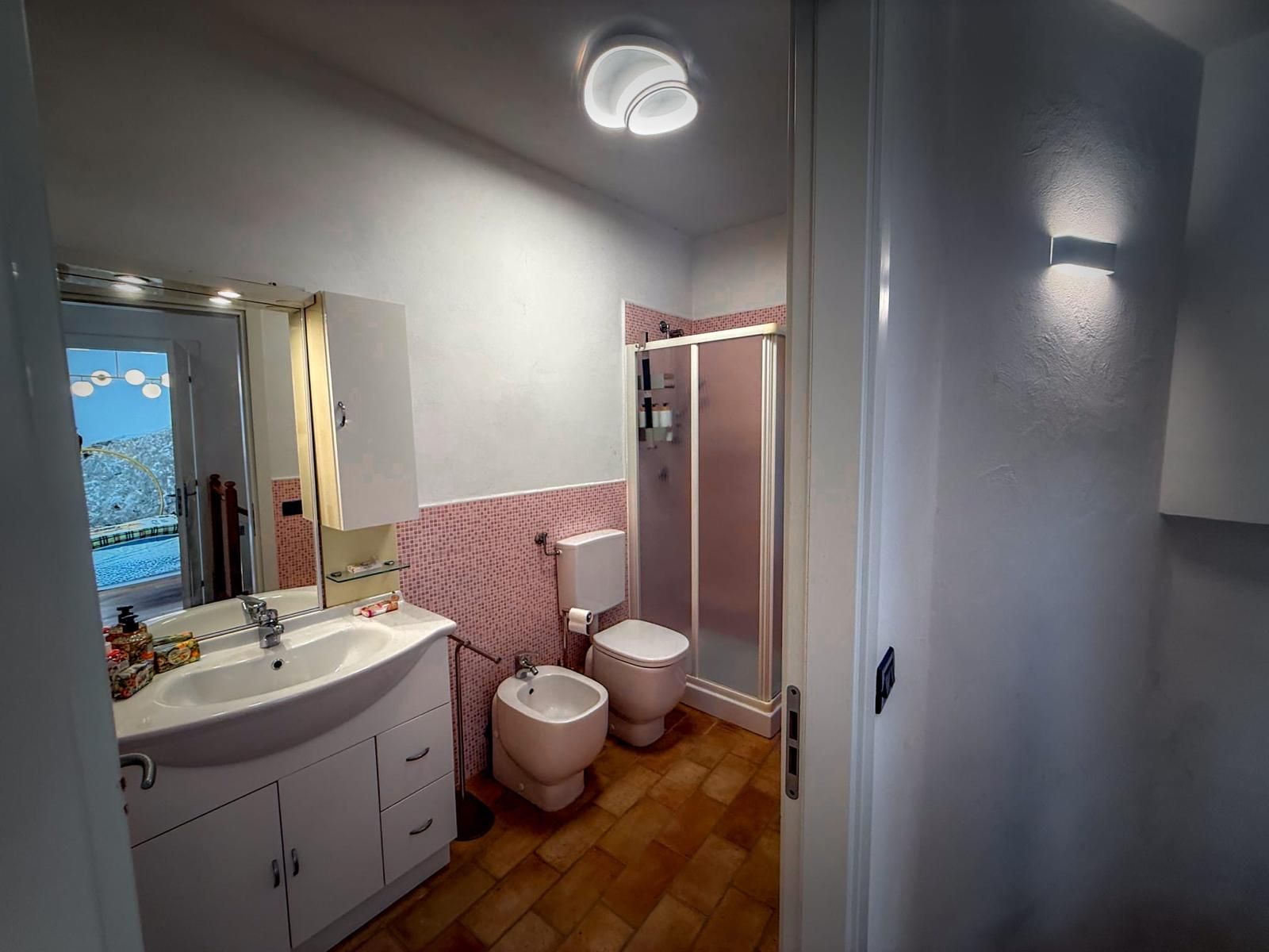 Un bagno completo di lavandino, specchio, water, bidet e doccia.
