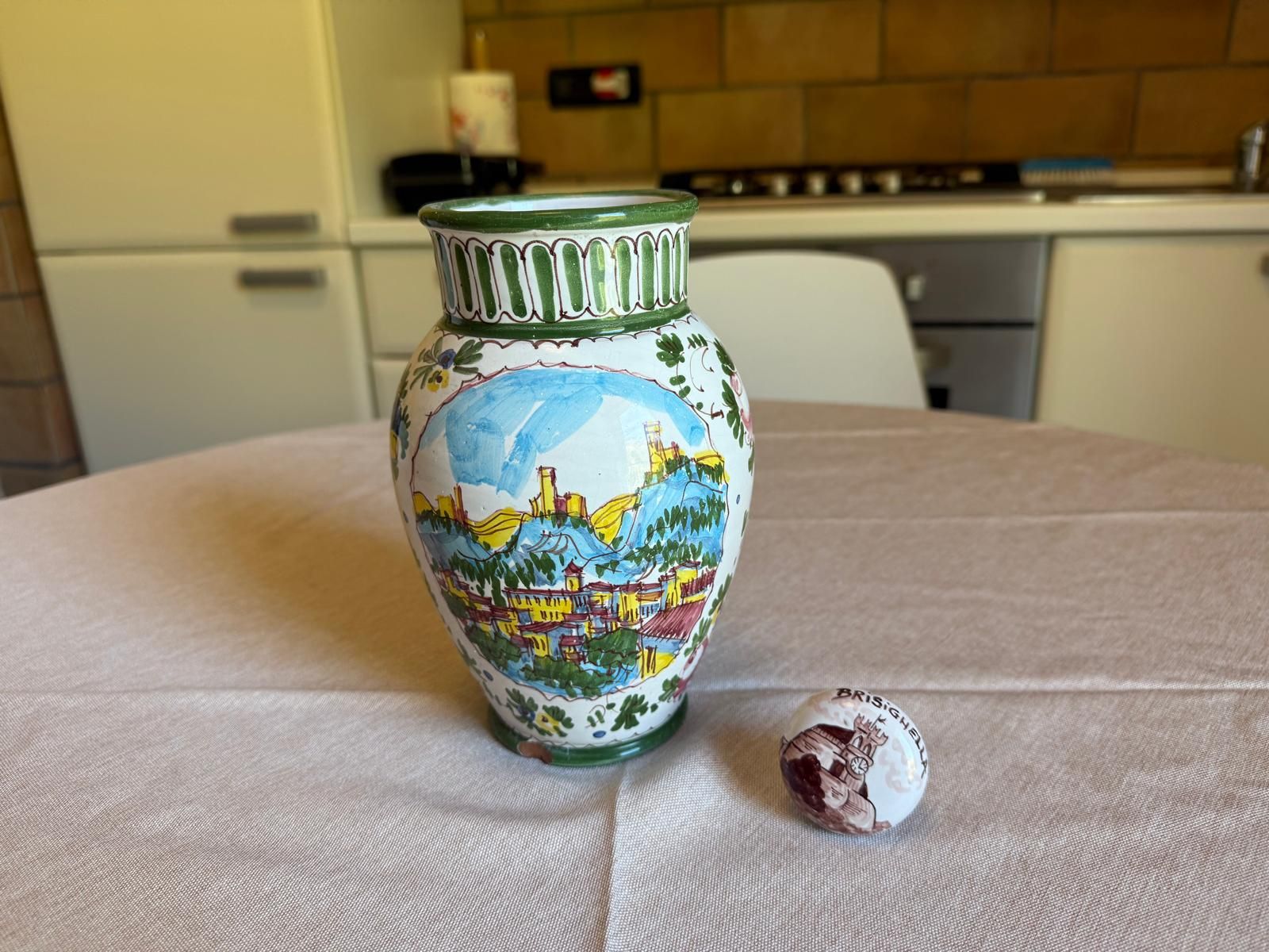 Eine Keramikvase mit einer gemalten Landschaft auf einem Tisch.