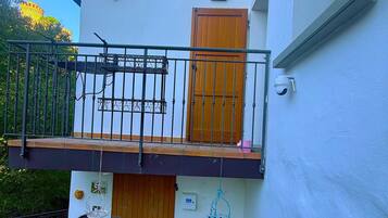 Un bâtiment à deux étages doté d’un balcon, d’une porte en bois et d’un petit jardin agrémenté de fleurs.