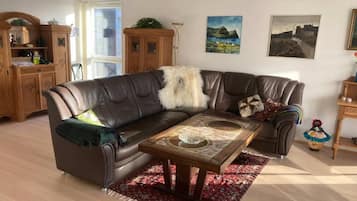 Een woonkamer met een leren modulaire bank, een houten salontafel en een rood tapijt met een patroon.