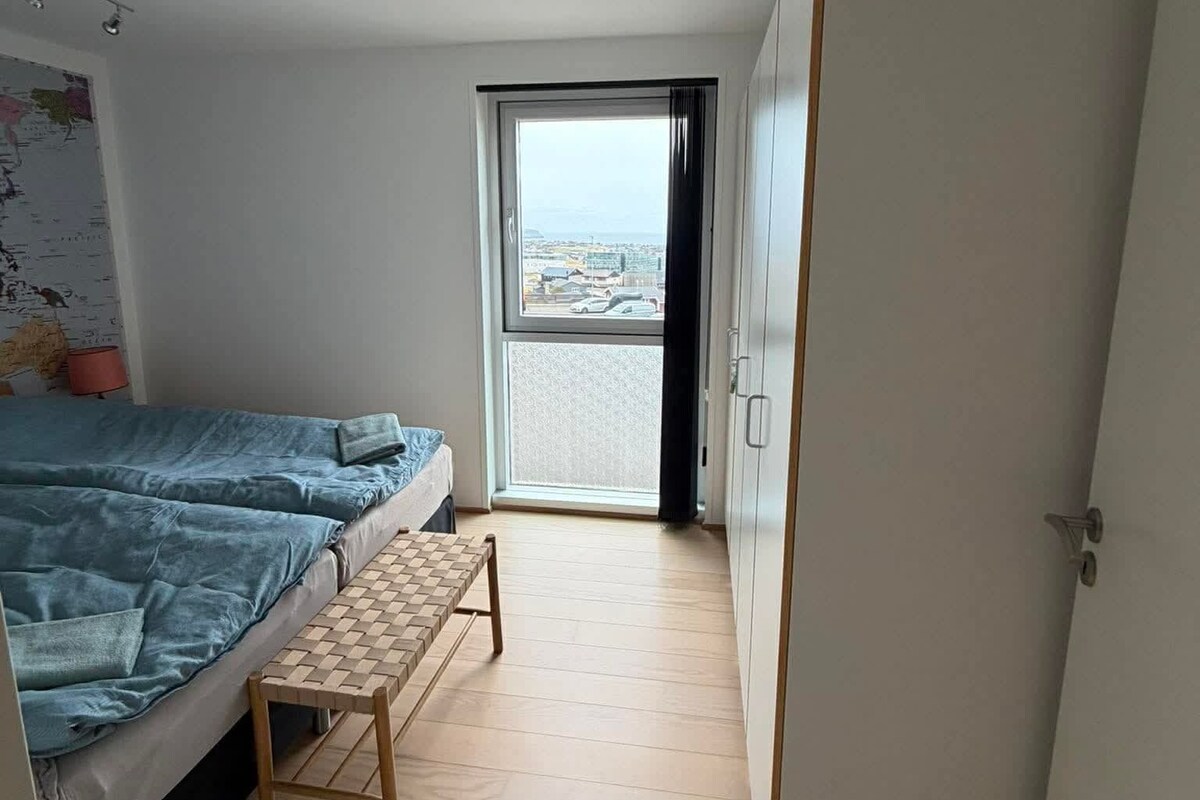 Un dormitori amb un llit, una taula petita, un armari i una vista per una porta.