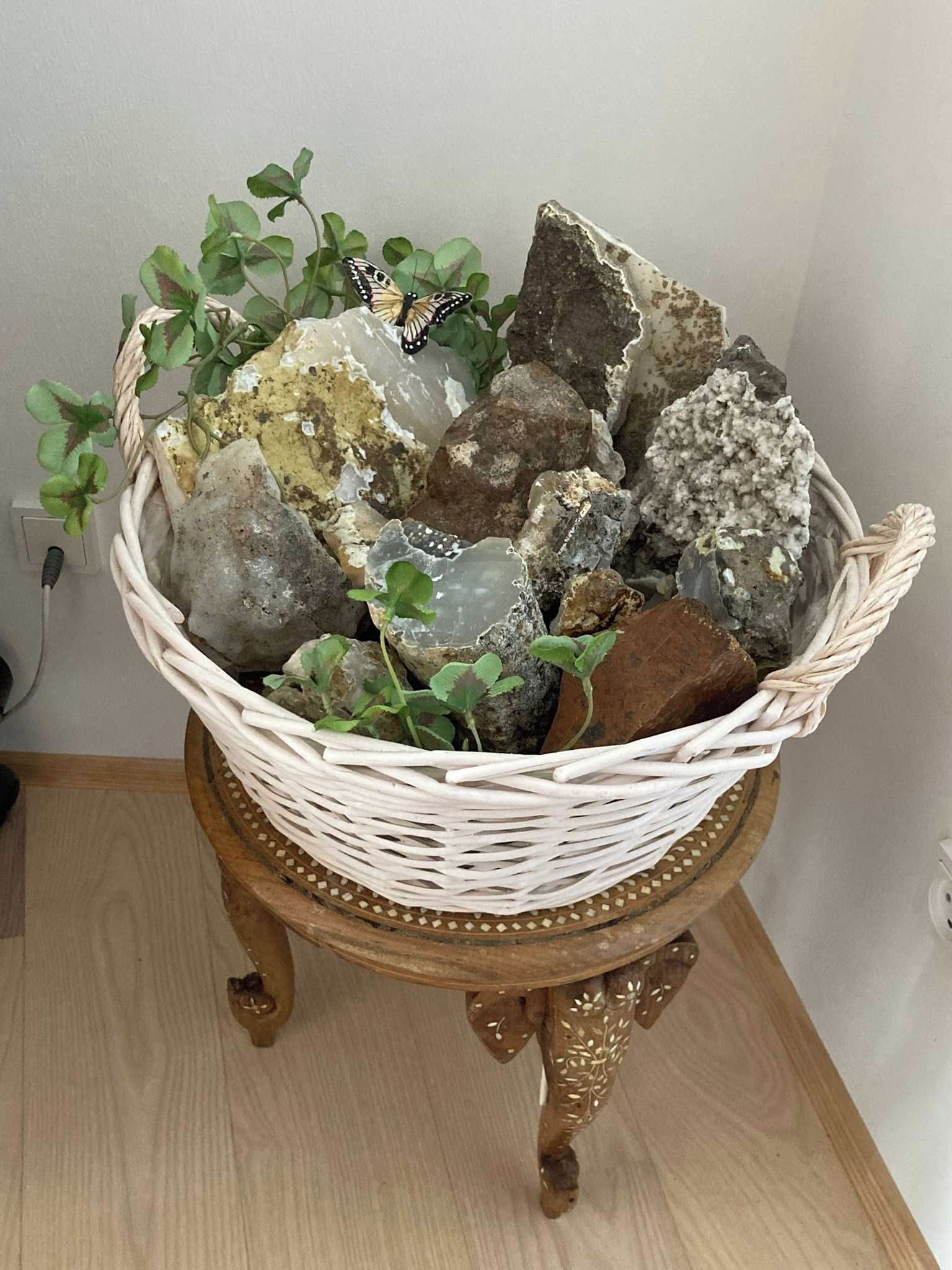 Una cesta de mimbre con piedras y plantas verdes sobre un soporte de madera.