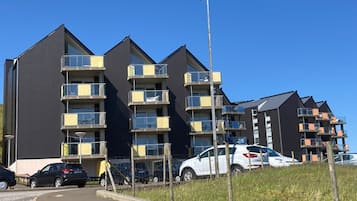 Een modern appartementencomplex met meerdere balkons en een parkeerplaats.