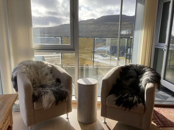 A room with two armchairs facing a large window overlooking a mountainous landscape.