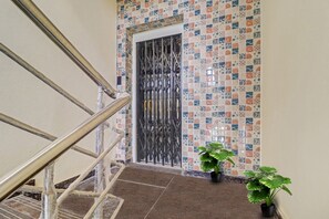 A staircase with a metal railing leading to a door with a decorative metal gate. There are two potted plants on the floor beside the door. - Collection O Elite Stay Near Habsiguda  (Hyderabad)