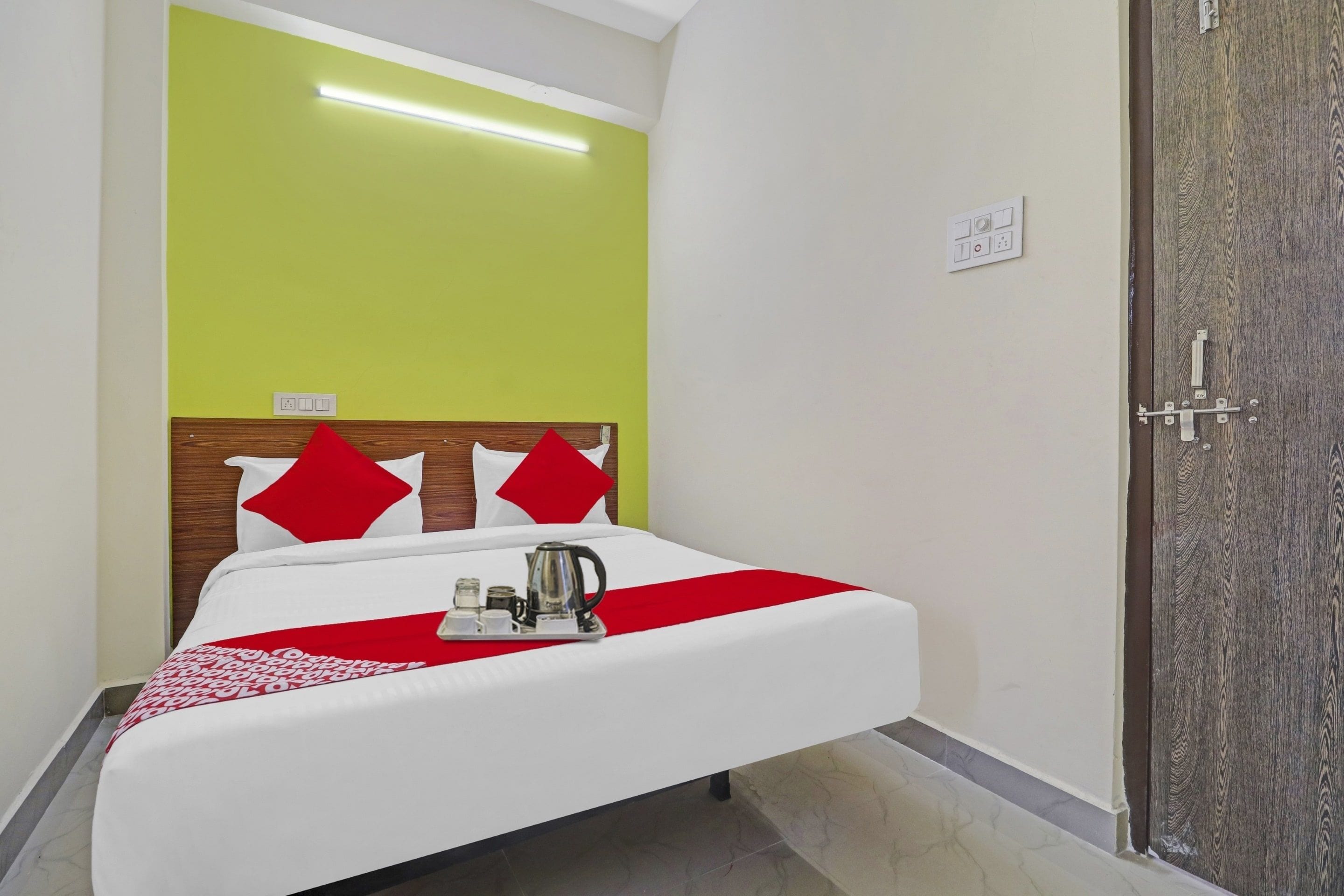 Una habitación de hotel con una cama, una bandeja con un hervidor y una puerta con manija.