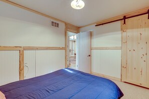 Ein Schlafzimmer mit einem Bett, einem Holzschrank und einer Tür zu einem anderen Raum.