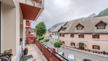 A balcony with potted plants, a table, and chairs.