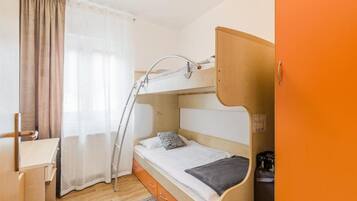Una cama litera con escritorio, silla, una escalera y un mueble pequeño.