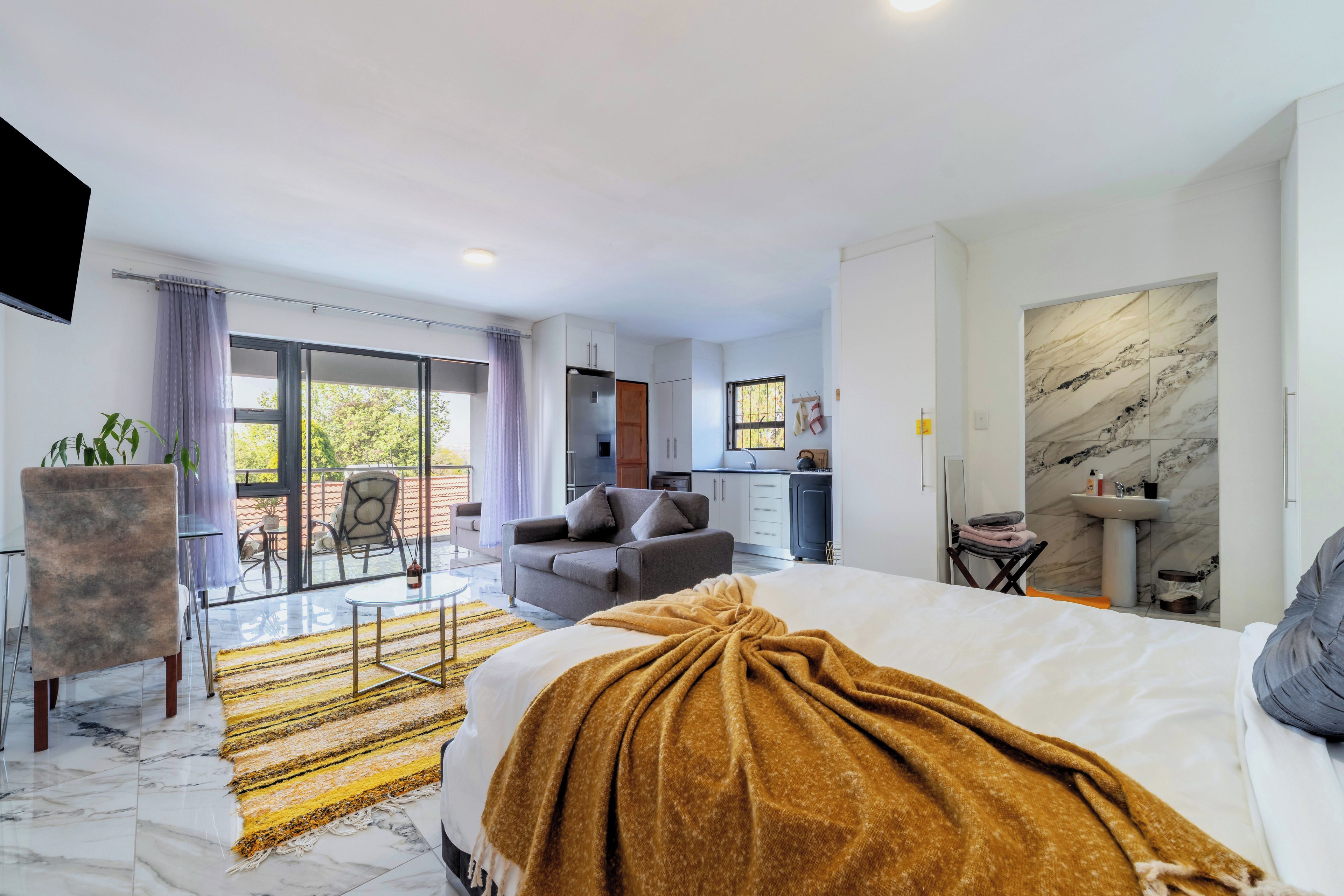 Ein modernes Hotelzimmer mit Bett, einer Couch, einem Essbereich und einer Küche.