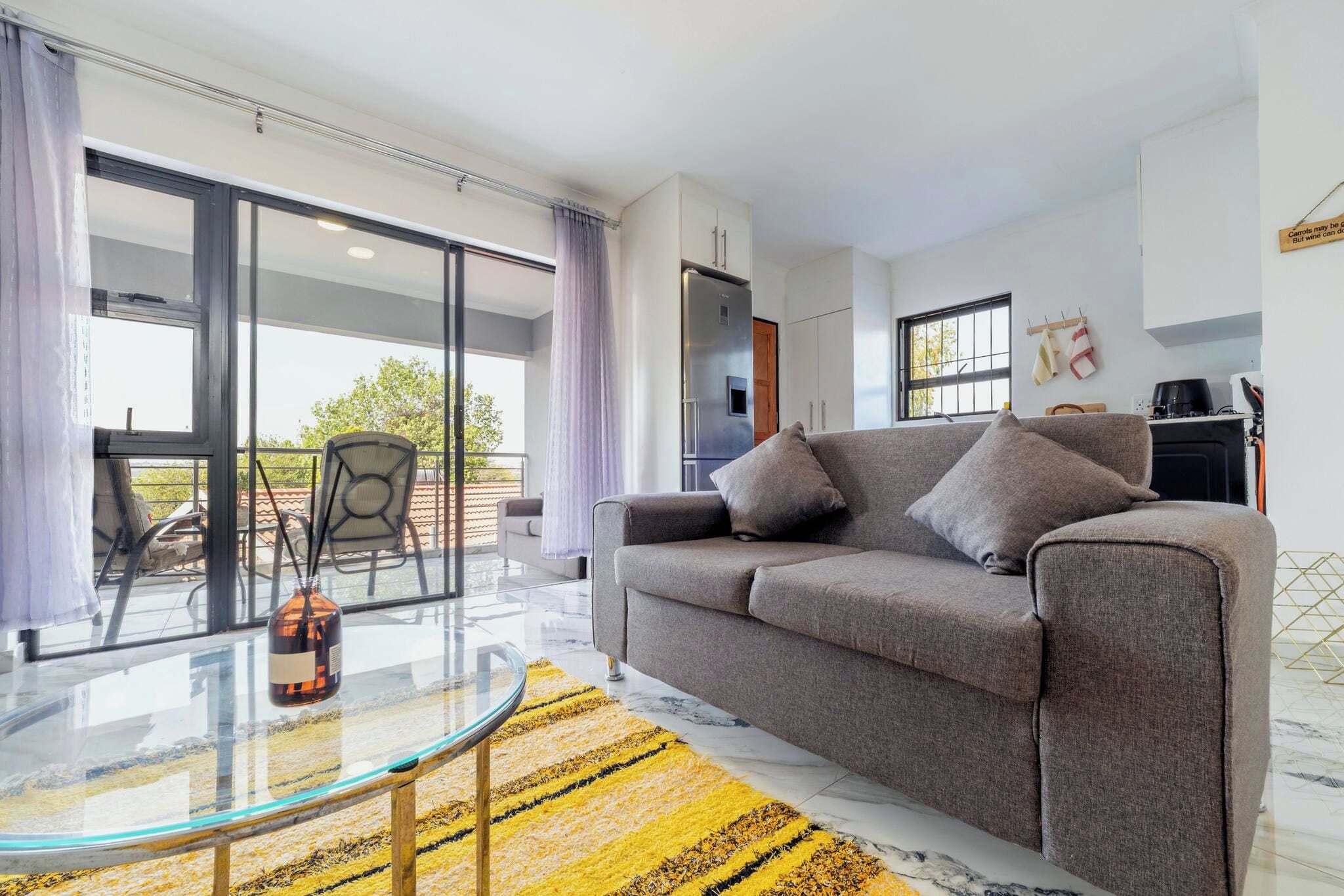 Una sala de estar moderna con un sofá, una mesa de centro de vidrio y vistas al exterior.