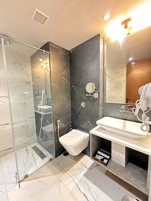 A modern bathroom with a glass-enclosed shower, a toilet, and a sink with a mirror. - TRINITY PALACE (Chas)