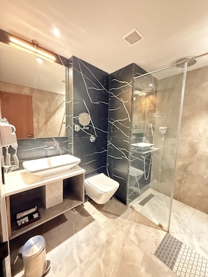 Une salle de bain moderne avec une douche en verre, un lavabo blanc et un sol carrelé en marbre.