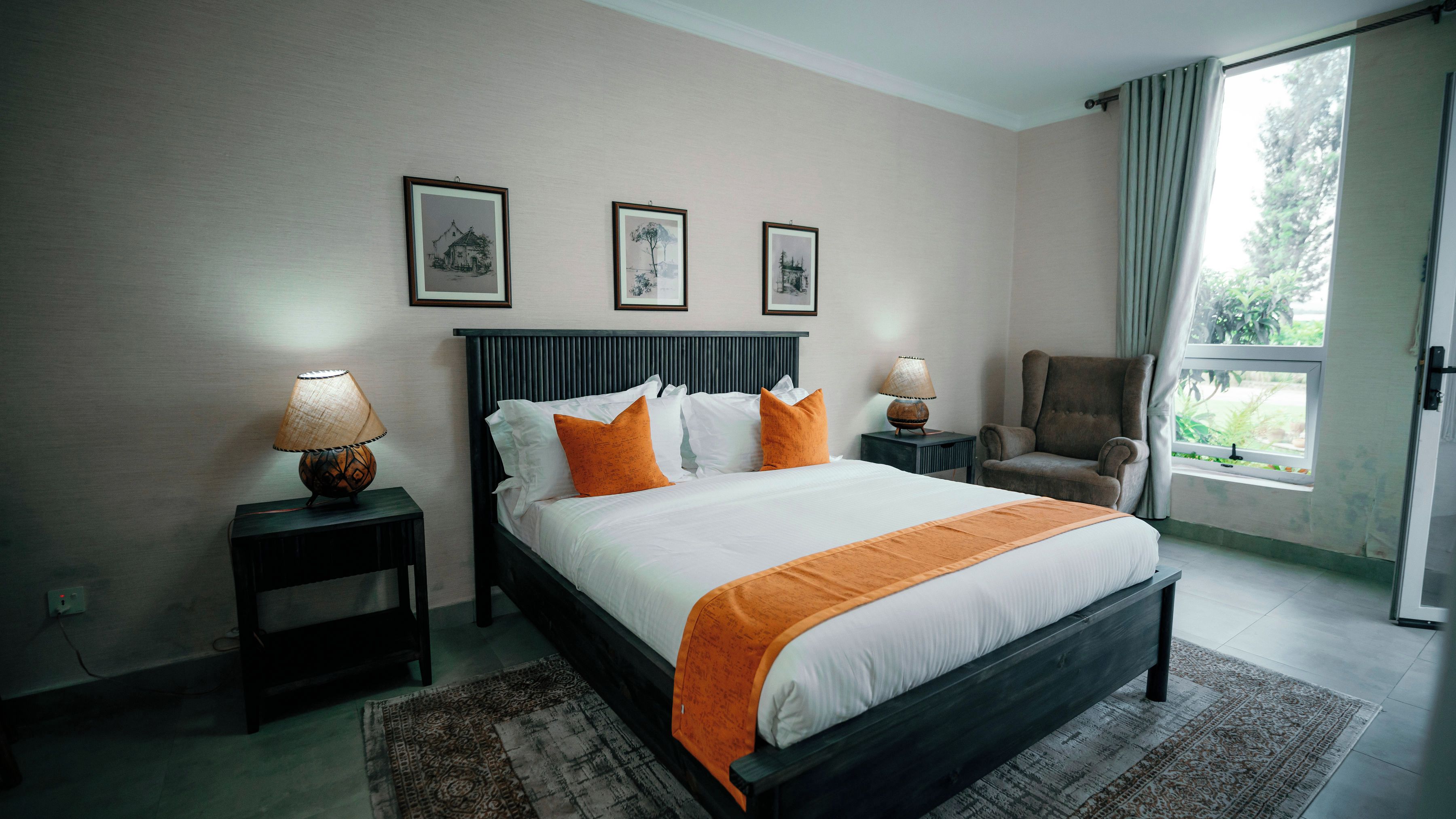 A hotel room with a bed, two bedside lamps, a chair, and a window with a view.