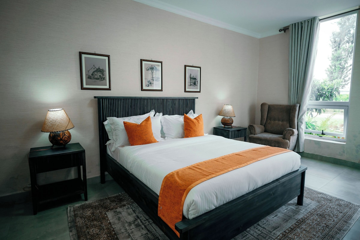A hotel room with a bed, two bedside lamps, a chair, and a window with a view.
