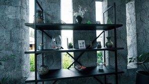 A black metal shelf with various decorative items against a textured wall.