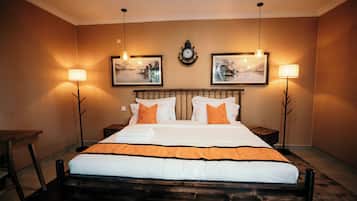 Una habitación de hotel con una cama, dos mesitas de noche, un reloj y dos lámparas de pared.