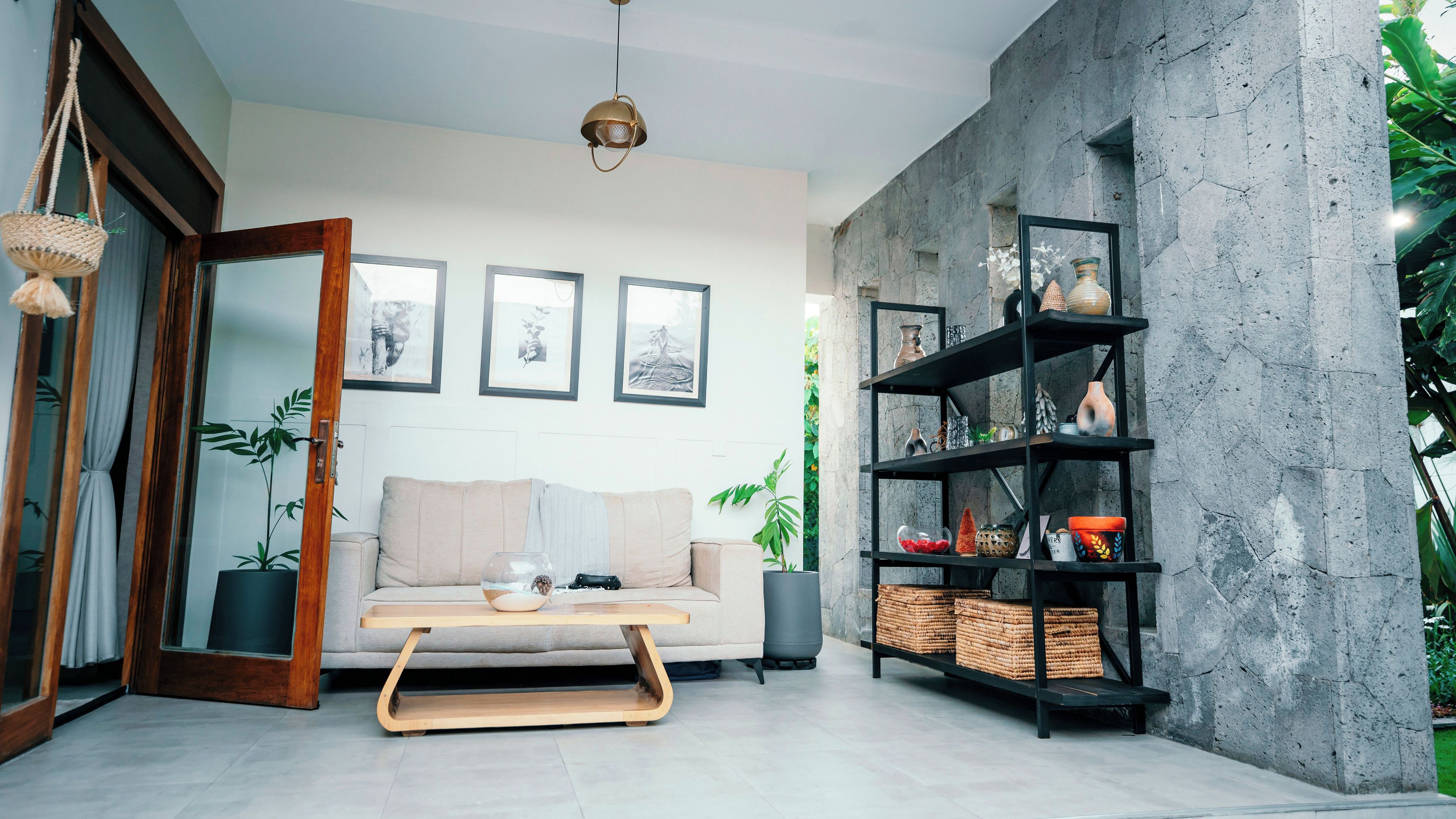 A modern living room with a sofa, coffee table, and a bookshelf against a concrete wall.