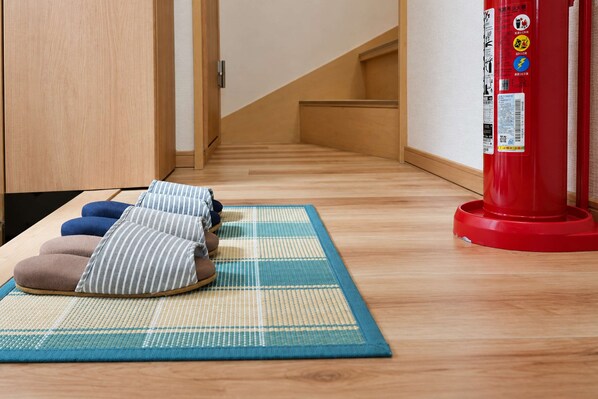 A tatami mat with cushions in a hallway with wooden flooring and a red fire extinguisher.