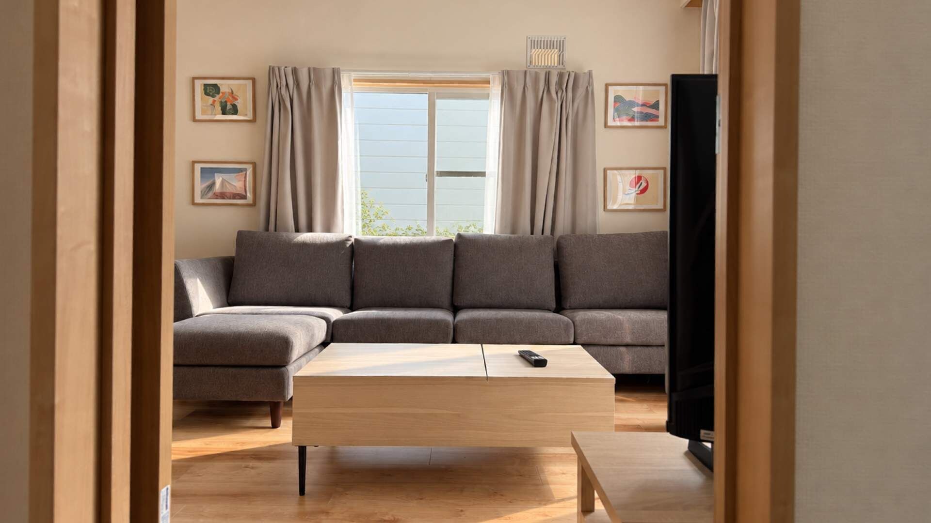 A living room with a sectional sofa, a coffee table, and a television.