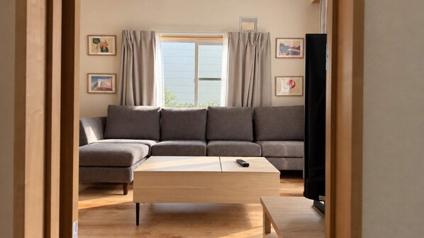 A living room with a sectional sofa, a coffee table, and a television.