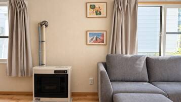 A room with a gray sofa, a wall-mounted air conditioner, and two framed pictures.