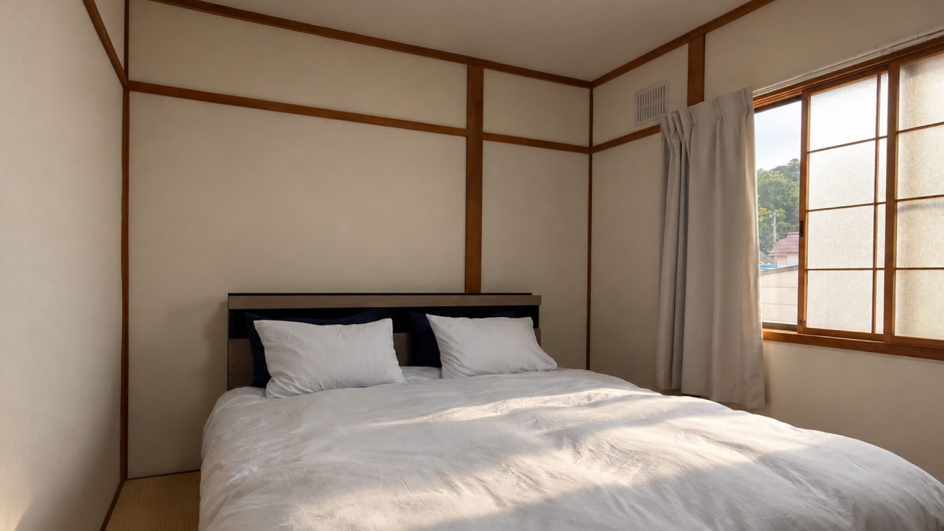 A bedroom with a bed, wooden paneling on the walls, a window with curtains, and a view of the outside.