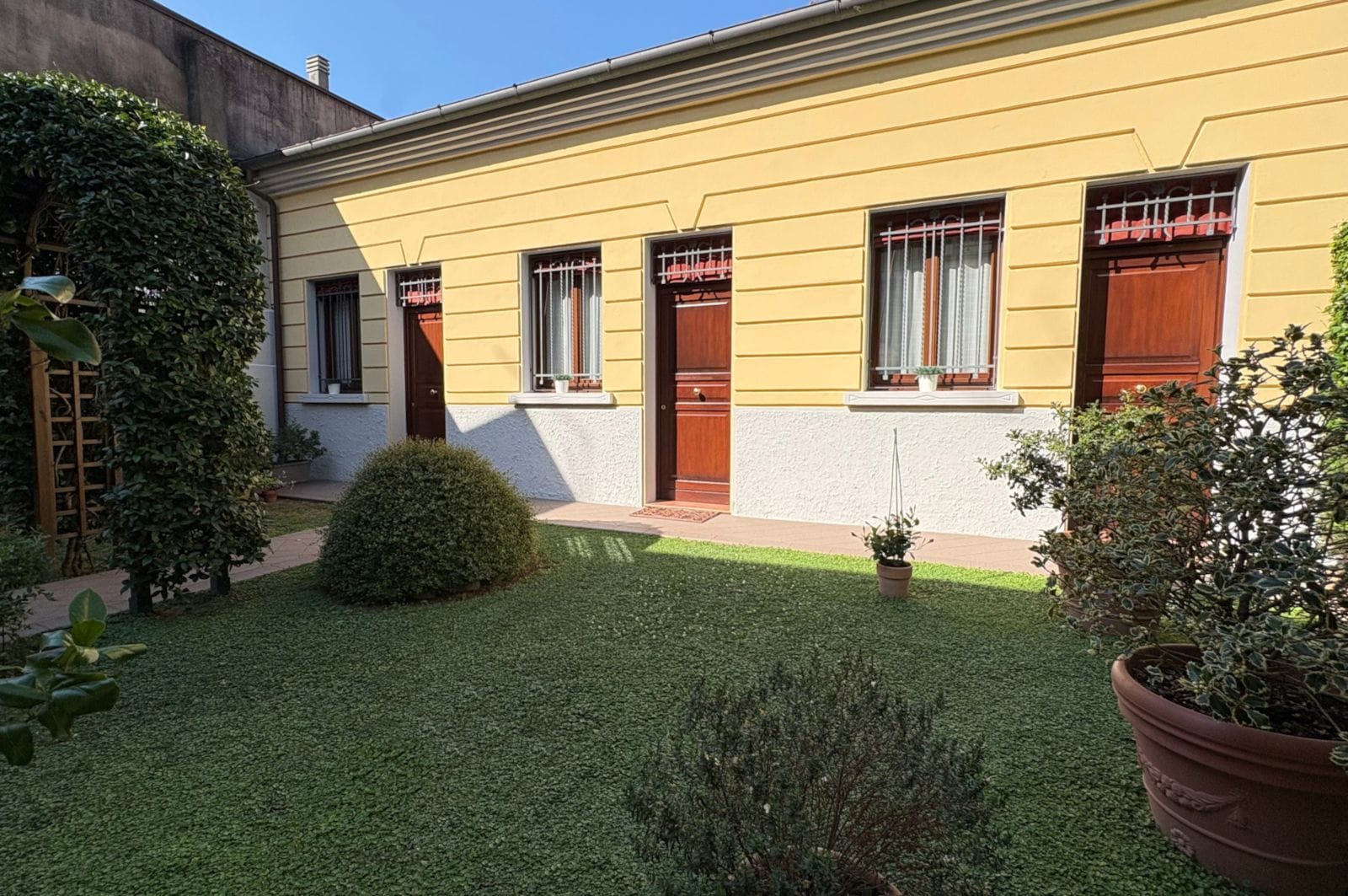Un bâtiment jaune avec un petit jardin devant.