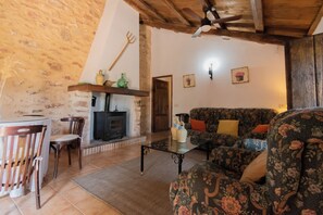 A rustic living room with a fireplace, a sofa, and a dining table. - Casa del Guarda - Finca & Spa Vereda Real (Albacete)