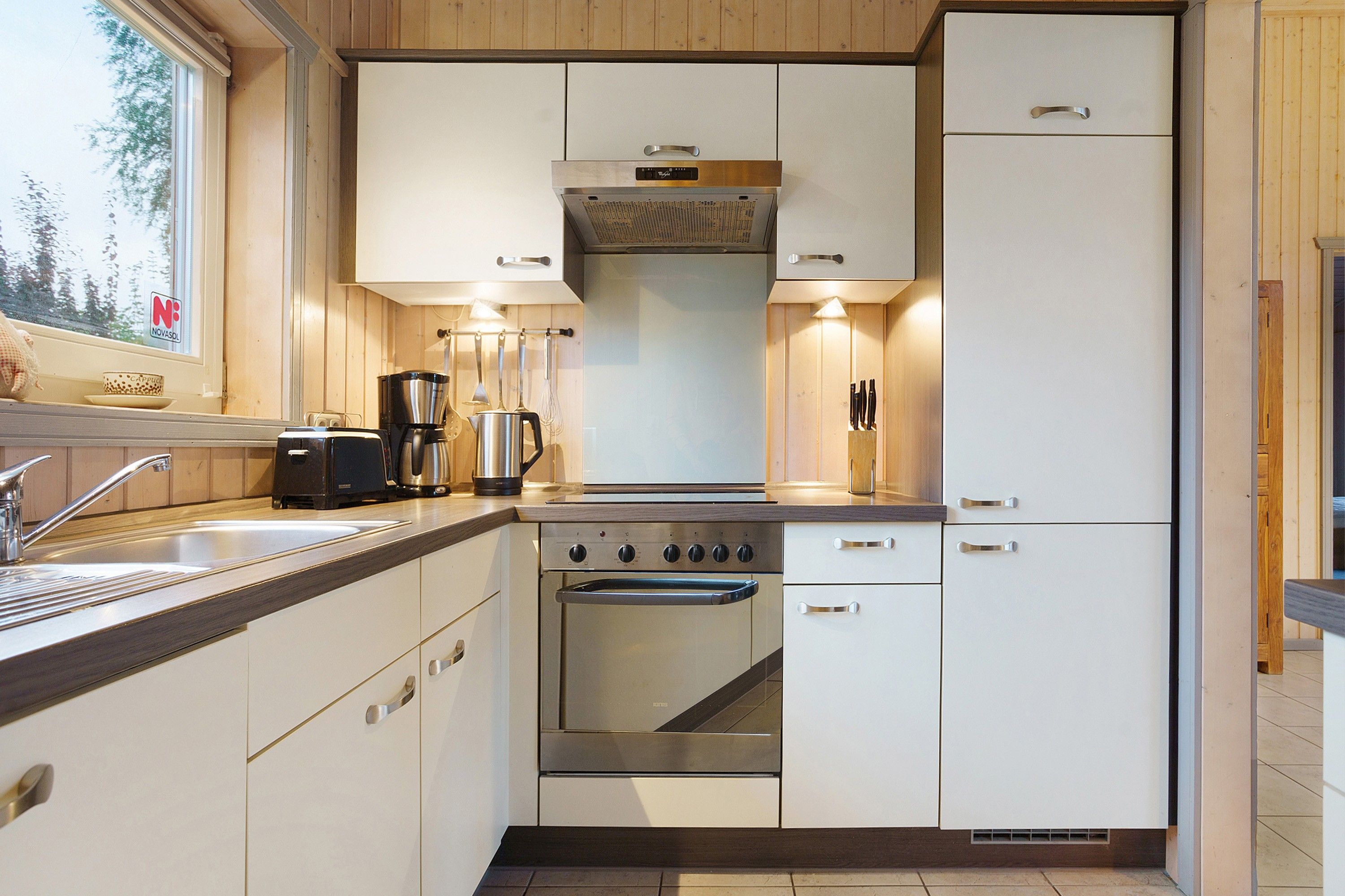A modern kitchen with white cabinetry, a built-in oven, and a coffee maker.