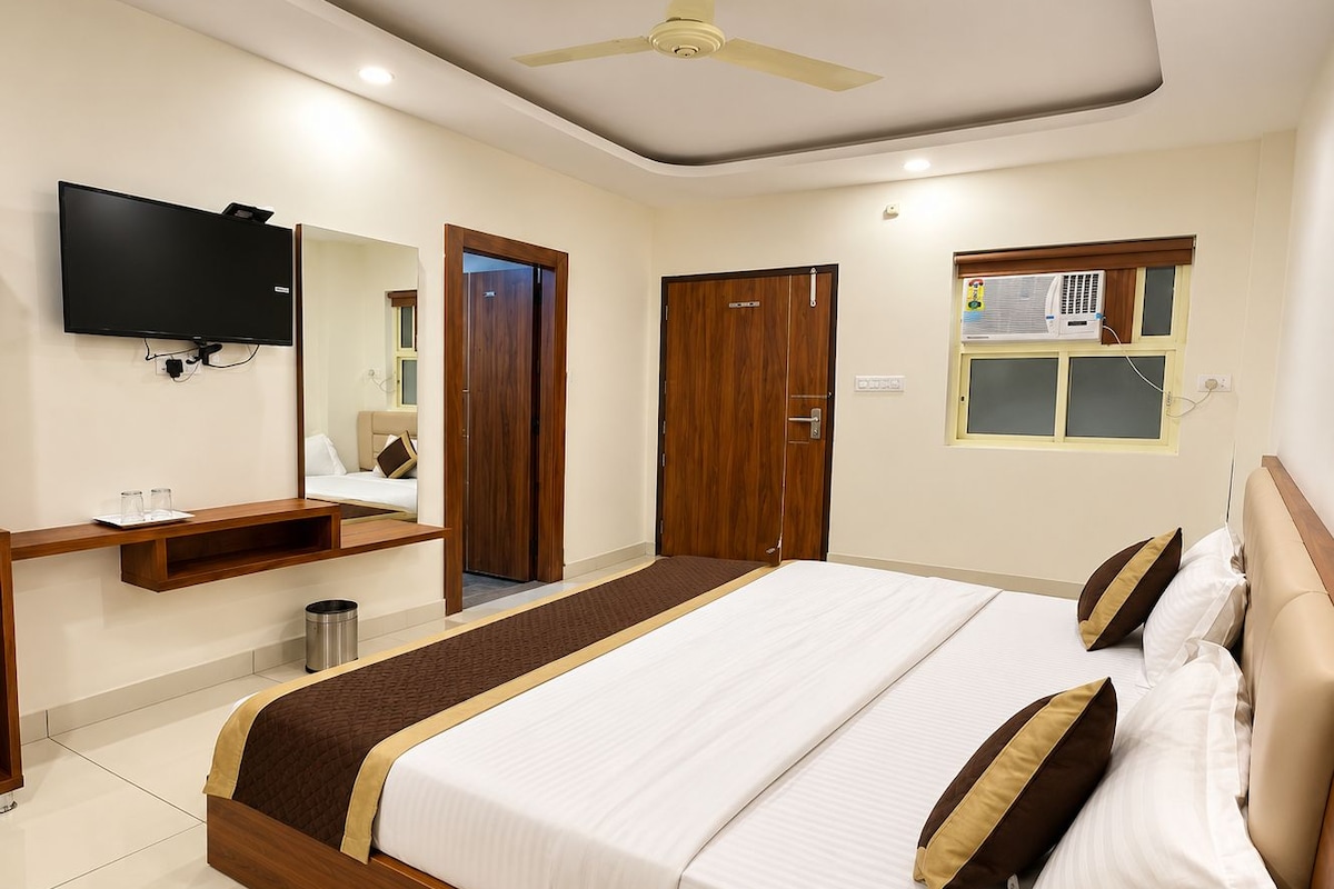 Una habitación de hotel con cama, televisión, armario, espejo y ventana.