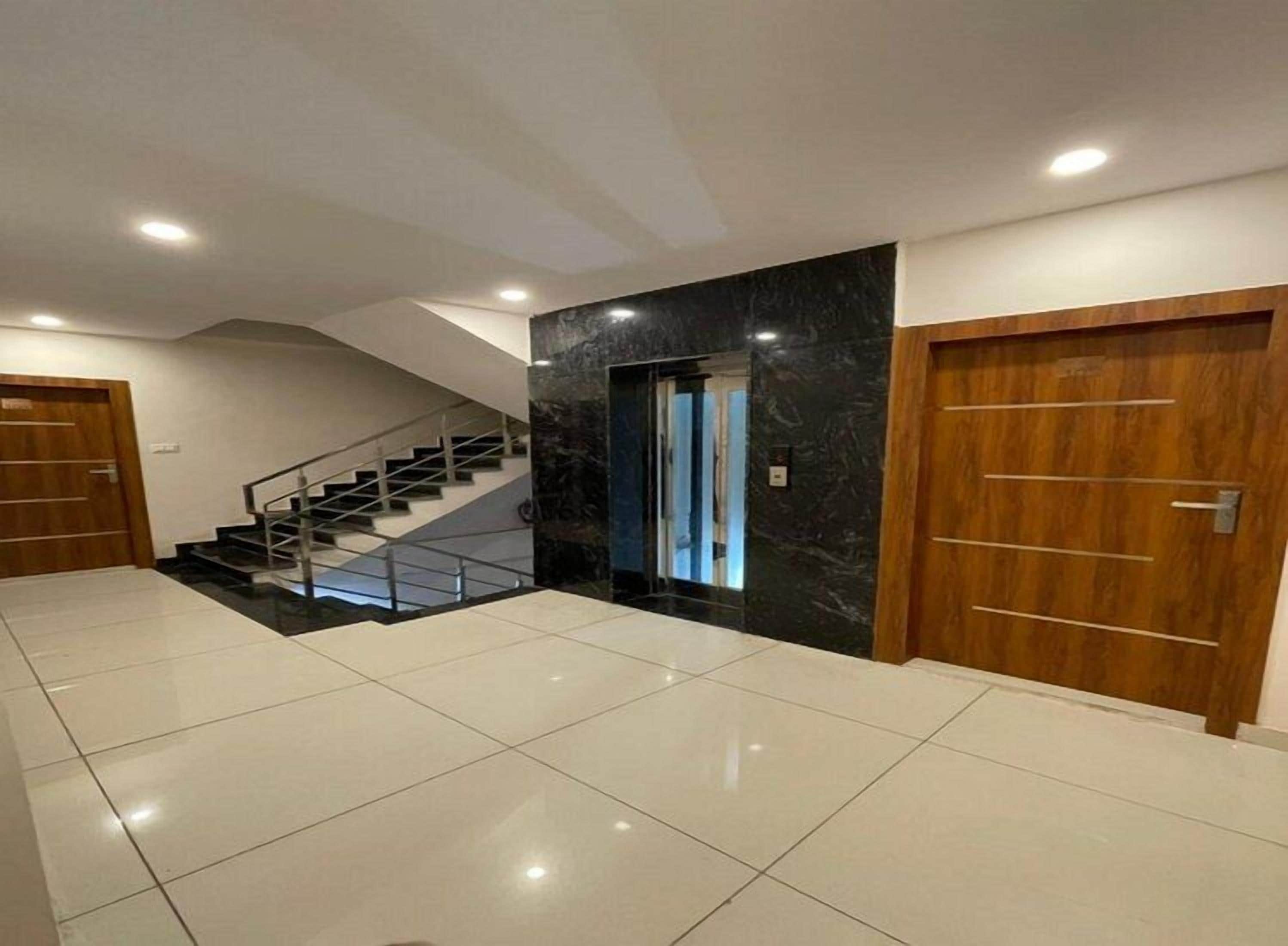 A spacious interior with a staircase, a door, and a tiled floor.