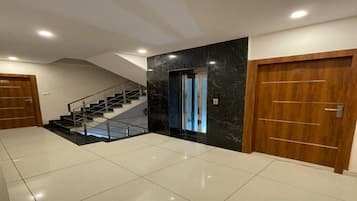 A spacious interior with a staircase, a door, and a tiled floor.