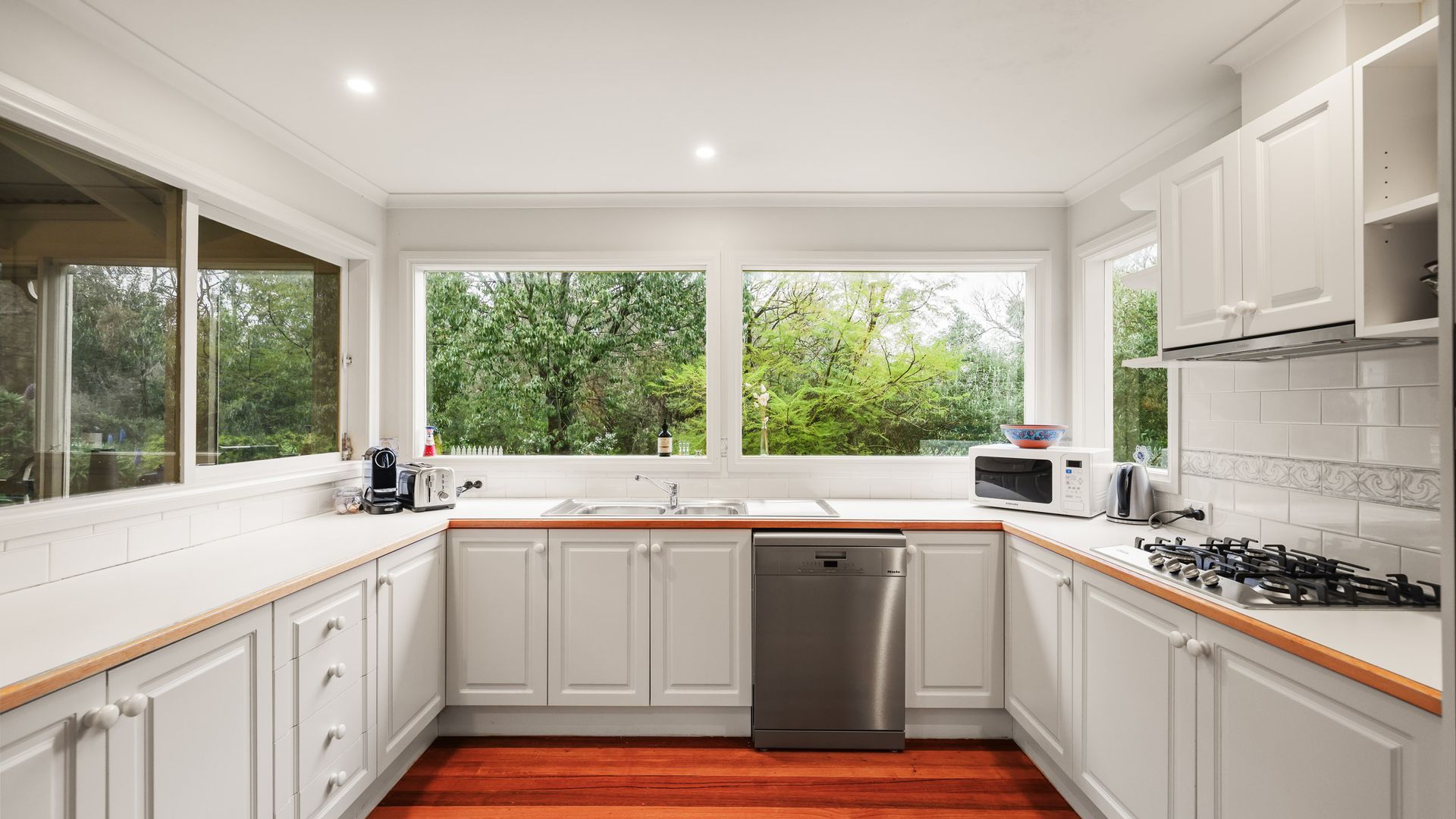 A modern kitchen with white cabinetry, a stainless steel dishwasher, a gas stove, and a microwave.