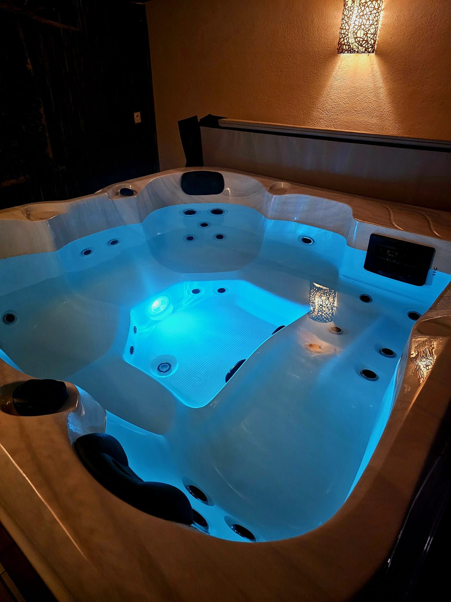 A hot tub with multiple jets, a control panel, and a textured surround.