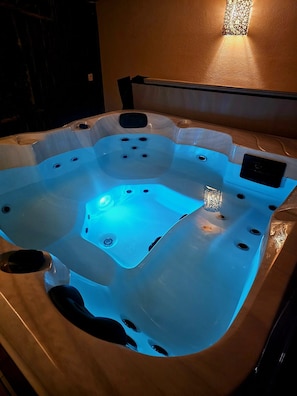 A hot tub with multiple jets, a control panel, and a textured surround.