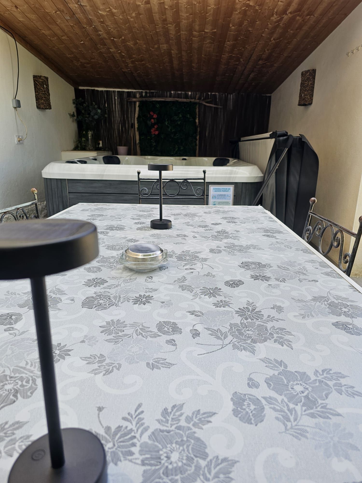 A room with a table covered in a floral tablecloth, a chair, and a small table with a glass top.