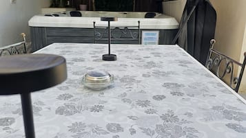 A room with a table covered in a floral tablecloth, a chair, and a small table with a glass top.