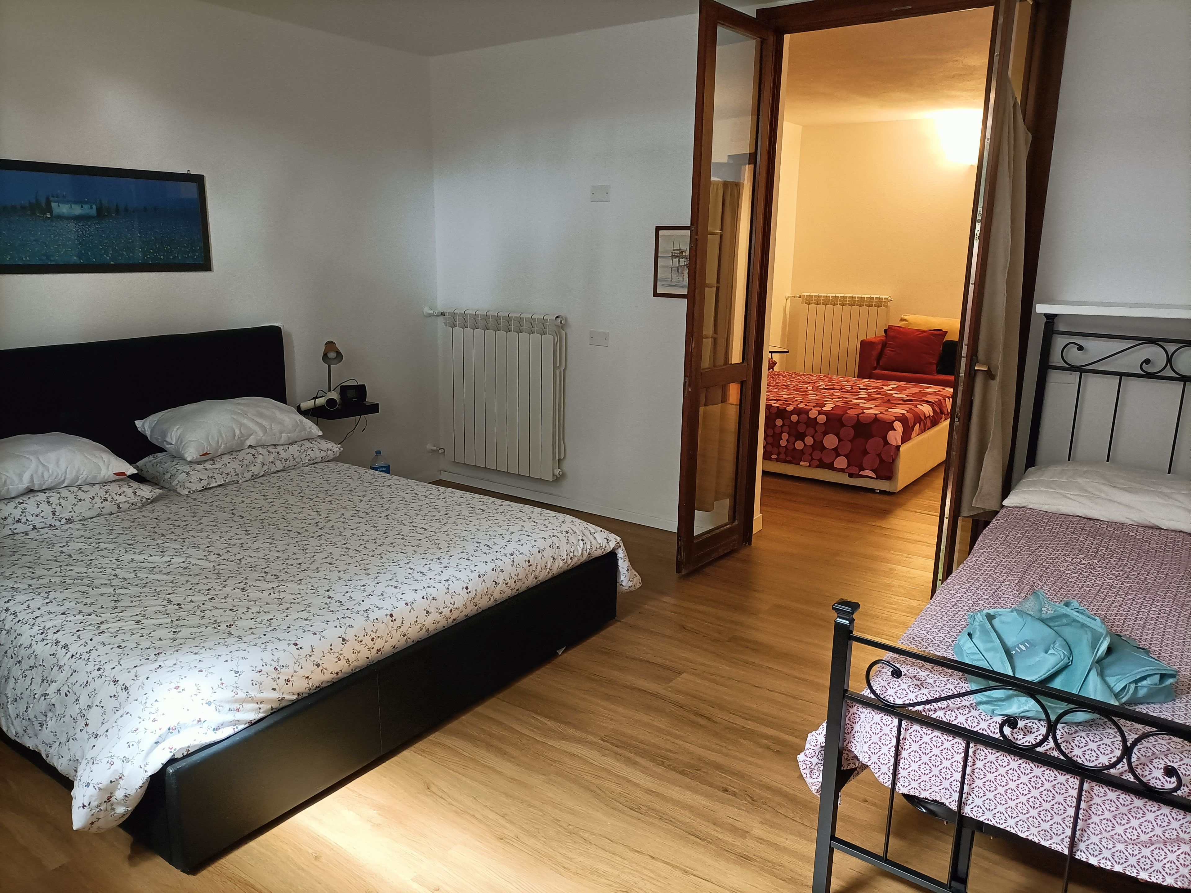 A bedroom with a bed, bedside table, lamp, and a radiator.