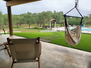 A hammock chair under a wooden pergola overlooking a pool and garden. - S'Ulivariu (Donigala Fenughedu)