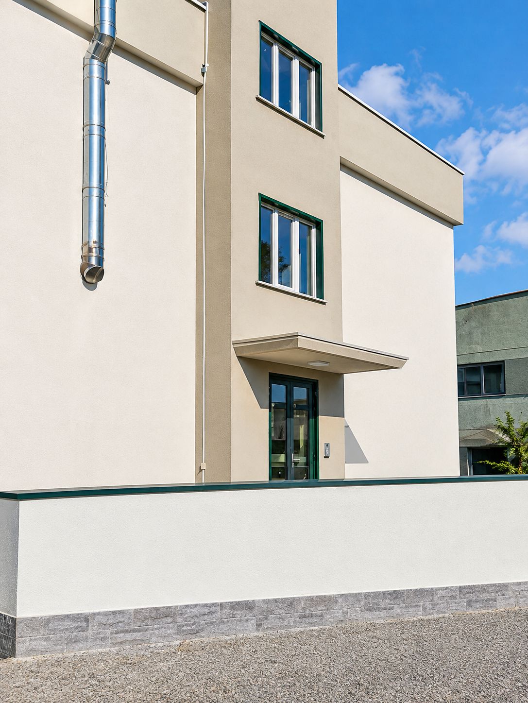 Un edificio moderno con facciata piatta, una finestra ben visibile e un ingresso.