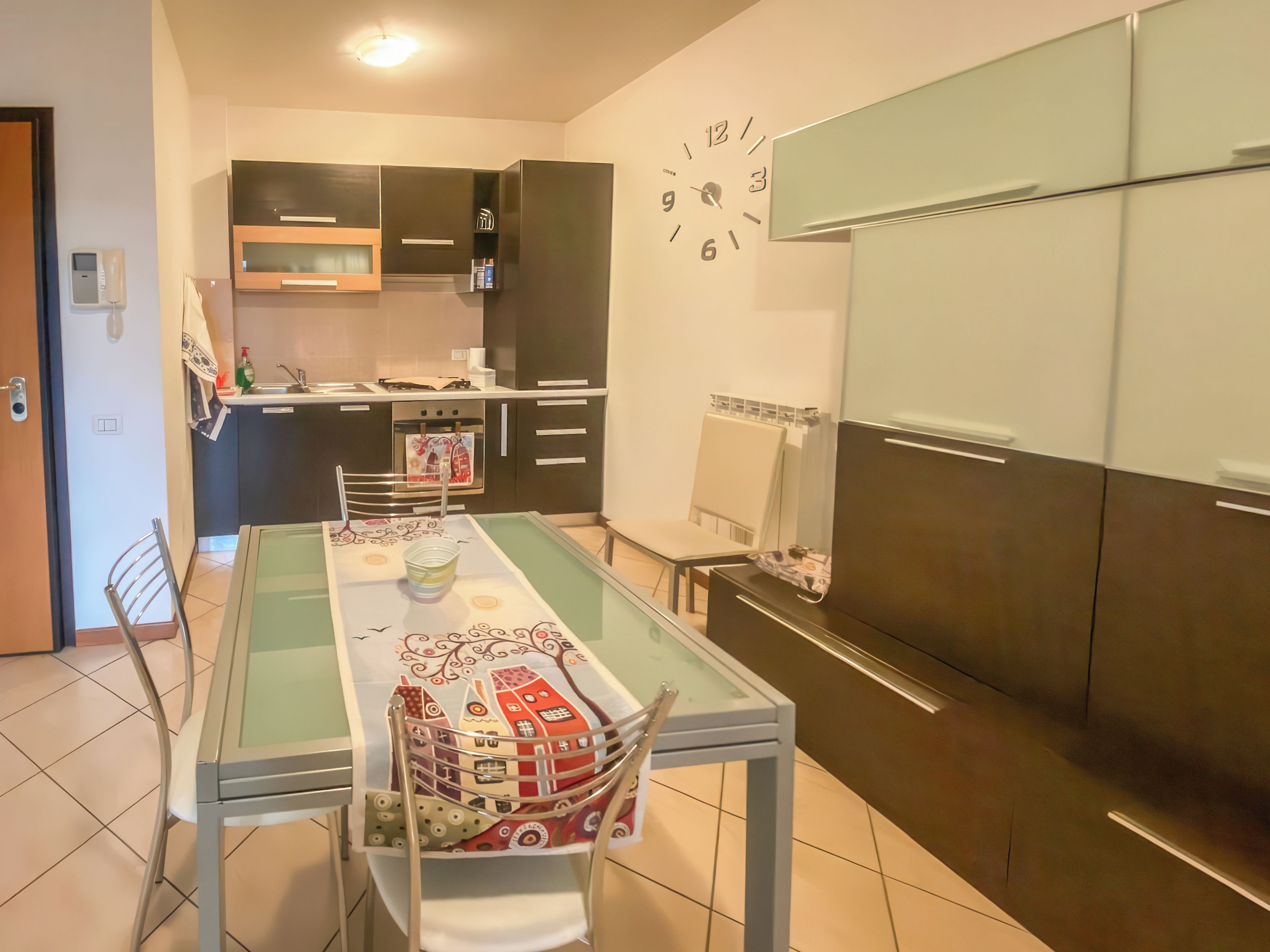 Una cocina moderna con una mesa de comedor, sillas y un reloj en la pared.