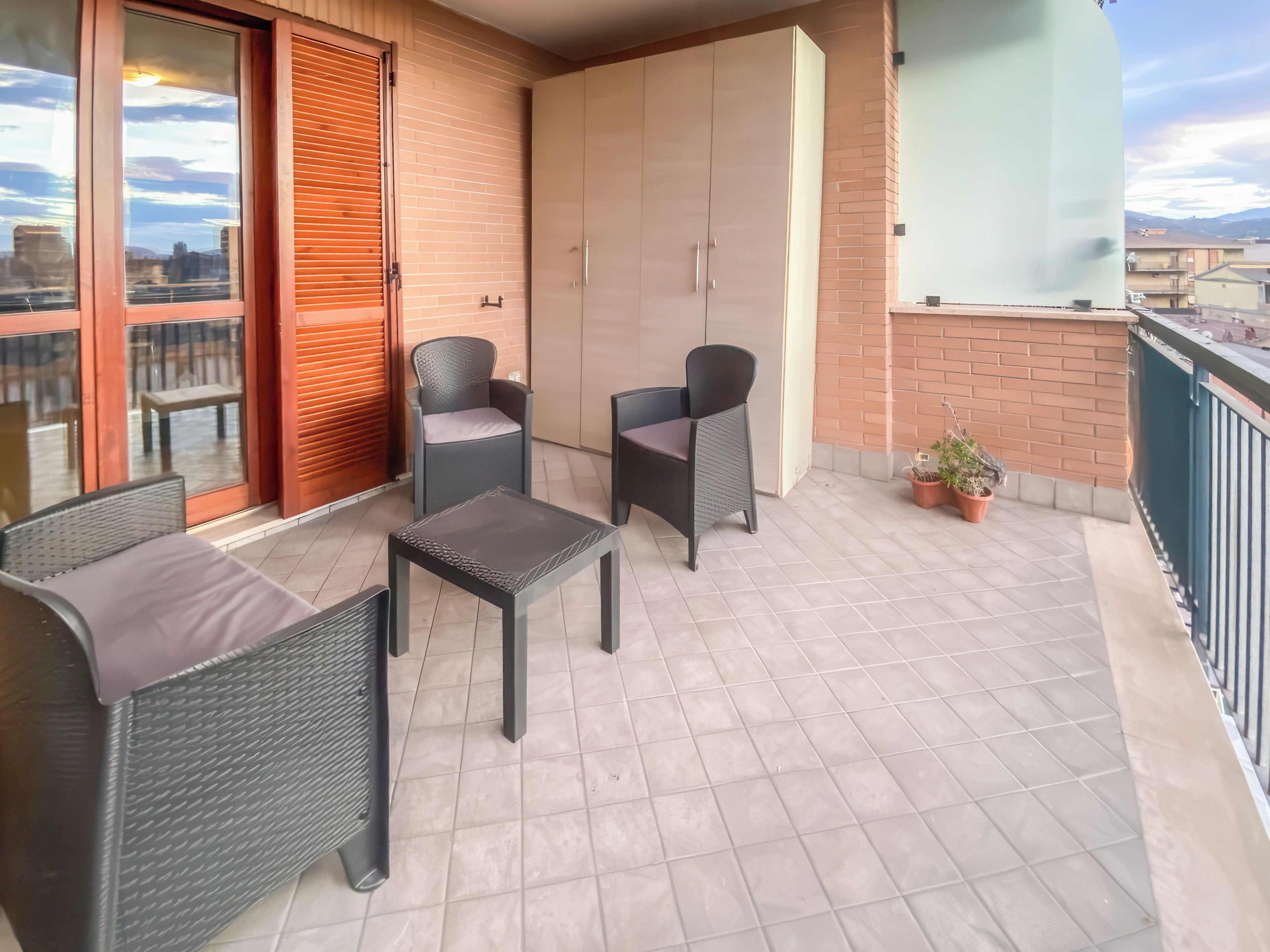 Un balcon aménagé avec du mobilier d’extérieur, une porte coulissante et une vue sur le paysage urbain.