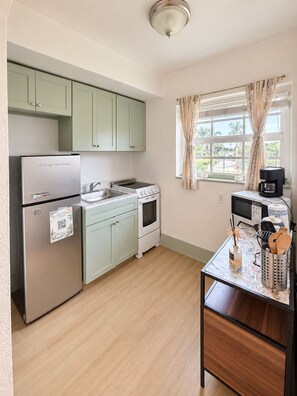 Una cocina compacta con refrigerador, estufa y microondas.