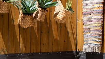 Un bain à remous doté d’un panneau de commande, un panier en osier contenant des plantes et une clôture en bois.