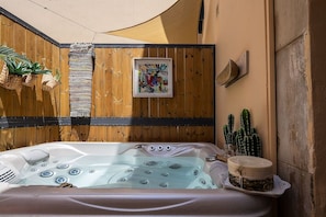 Een hottub met een houten wand en een cactuss.'