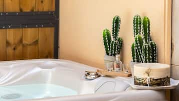 Un bain à remous avec un mur en bois et deux cactus en pot.