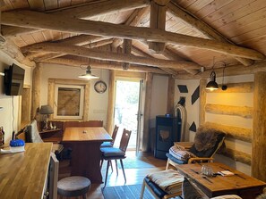 Ein rustikales Interieur mit Holzbalkendecke, einem Esstisch mit Stühlen, einer Couch und einem Kamin.