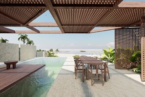 Ein Pool ohne erkennaren Rand mit einer Holzdielen-Terrasse, Sitzgelegenheiten im Freien und Blick auf das Meer.